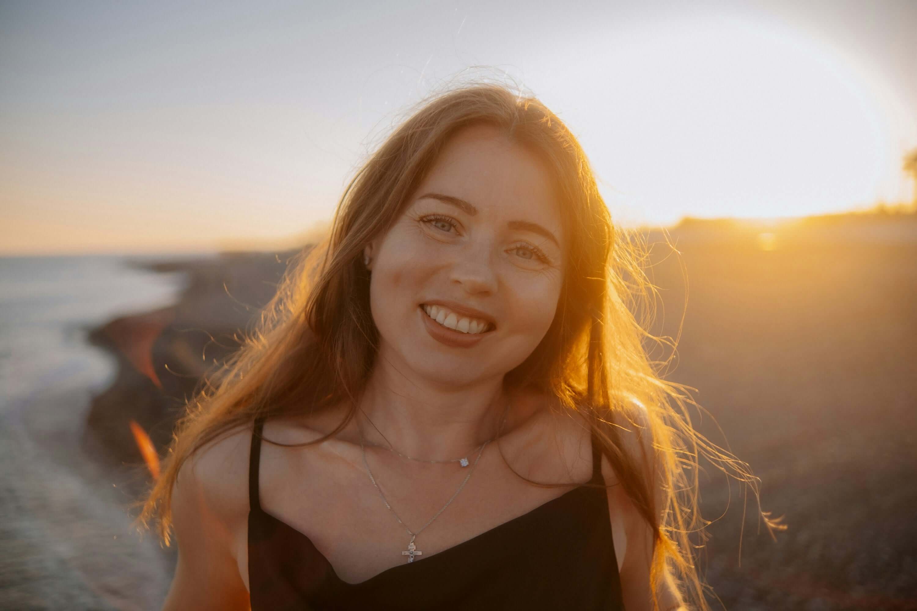 Woman smiling on a beach with sunset light